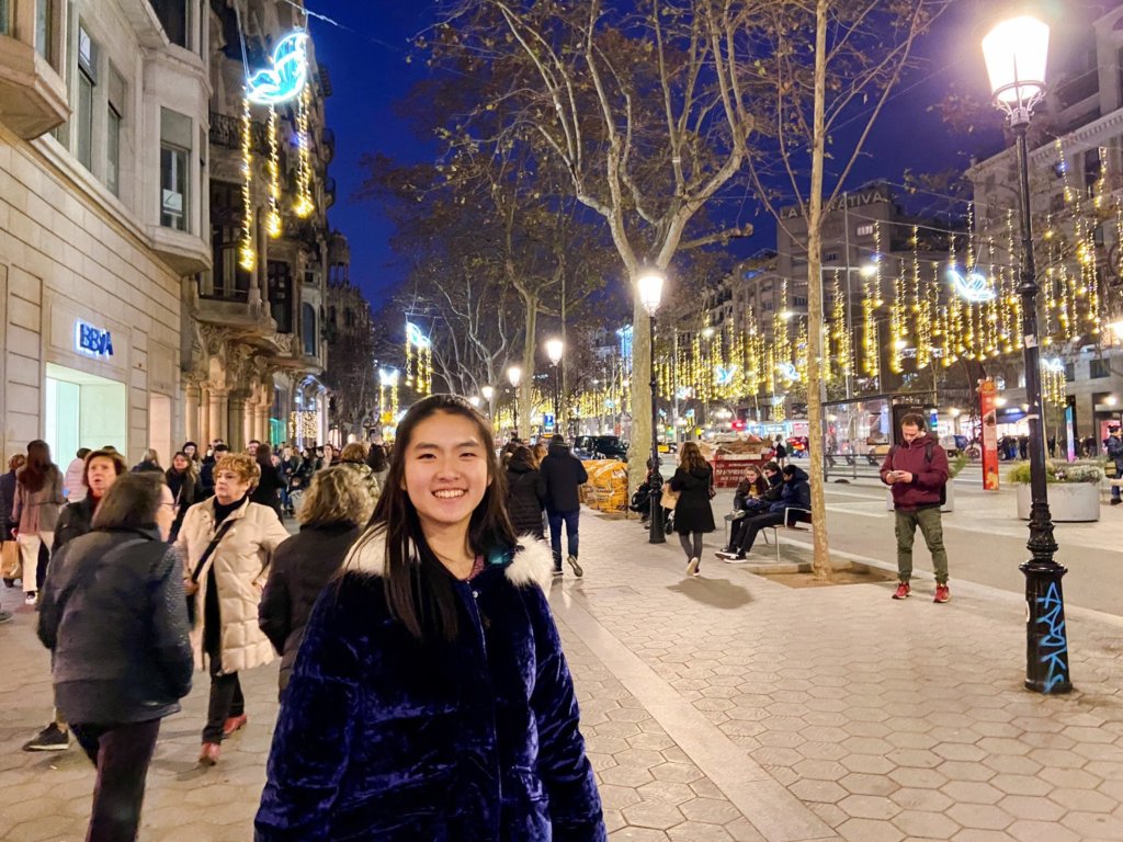 Photo of Angela Ji on busy street with Christmas lights in background